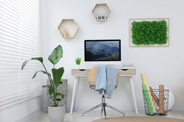 Canvas Print - Green artificial plant wall panel and desk with computer in light room. Interior design