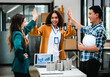 © makibestphoto - Diverse team with Asian man, African American woman, Caucasian woman discussing a clean energy city planning project with building models and solar panels.