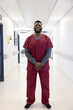 Portrait of happy african american male doctor standing in hospital corridor