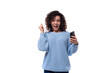 young pretty woman with curly method hairstyle smiling holding smartphone in her hand