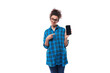 cute young pretty woman with curled hair in a blue shirt shows the screen of a smartphone with a mockup