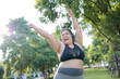Cheerful plus size asian woman in fitness wear exercising in park. Healthy Concept.