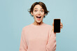 Young surprised woman wear beige knitted sweater casual clothes hold in hand use blank screen mobile cell phone chatting online isolated on plain pastel light blue cyan background. Lifestyle concept.