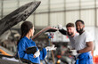 © Wosunan - Car mechanic working in an auto repair shop, inspecting the operation of the car's air conditioner and refrigerant, Focus on woman