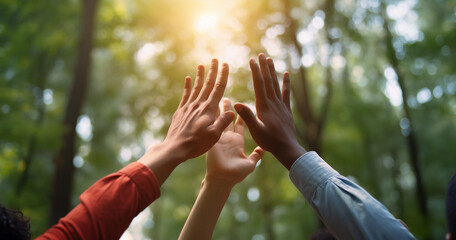 Environmental conservation concept with mixed race group of people giving high five in green forest