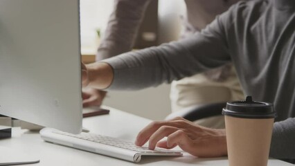 Two Biracial male programmers looking at computer screen and discussing program or application while working in team at modern open space office