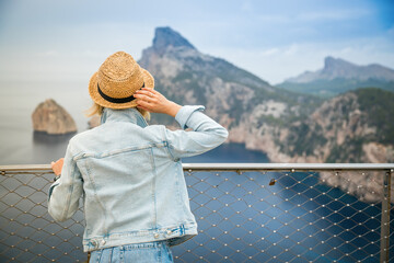 Wall Mural - Woman in straw hat looking at the Cap de Formentor