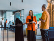© .shock - A group of young business colleagues, including a woman in a hijab, stands united in the modern corridor of a spacious startup coworking center, representing diversity and collaborative spirit