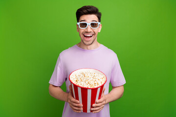 Wall Mural - Portrait of impressed person with stubble wear violet t-shirt in 3d glasses hold popcorn watch film isolated on green color background