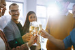 © maxbelchenko - Colleagues in the office celebrate the concluded deal with champagne and sparkling wine. A group of people with glasses of champagne having fun, relaxing in the office. Concept of work, holiday.