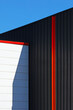 Architecture industrielle noir et couleur en habillage métallique d'un mur de façade de bâtiment moderne dans une zone commerciale.