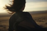 Fototapeta  - A solitary woman stands amidst a vast desert landscape, captured in full focus against a backdrop of windswept sands.