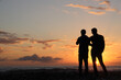 © Maxim Chuev - Standing gay two men couple close to each other in front of sea coast background. black silhouette of pair of 2 gays on the beach and sunset. back rear view.