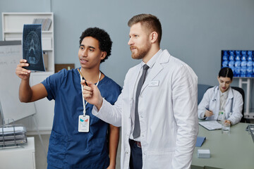 Wall Mural - Waist up portrait of two doctors discussing brain X-ray image standing in medical clinic, copy space