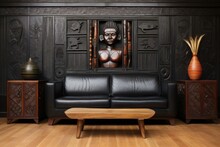 Traditional African-inspired Decor, Black Leather Sofa, Wooden Coffee Table, Carved Wall Panel, Tribal Statue, Patterned Vase, Dark Textured Wall, Wooden Flooring