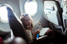 Young Girl Using Digital Tablet During An Airplane Flight