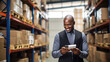 Smiling man standing in a warehouse aisle, using a smartphone possibly to manage or check inventory.