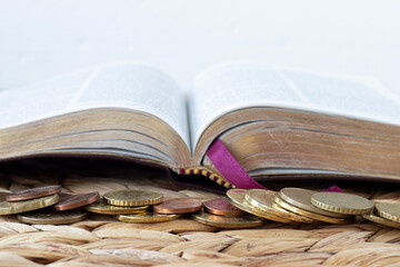 Wall Mural - Coins money in front of open holy bible book with white background. Close-up. Copy space. Selective focus. Christian tithing, generosity, finances, budget, and contribution concept.