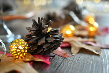 Autumn Fall Season Thanksgiving table decorations with pine cones, leaves & lights