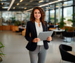 © Favio - mujer exitosa latina sonriendo y sosteniendo una tableta digital en una oficina