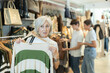 © JackF - elderly lady carefully examines selection of sweaters, searching for ideal one to keep her warm.