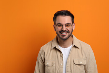 Poster - Portrait of smiling man in stylish glasses on orange background. Space for text