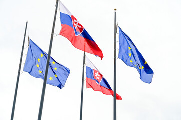 Flags of Slovakia and European union in front of Parliament in Bratislava. Waving flags of Slovak Republic and EU on flagpole. Slovakia's national coat of arms.