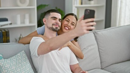 Wall Mural - Beautiful couple making fun selfie memories on sofa, confidently smiling and expressing love at their cozy home