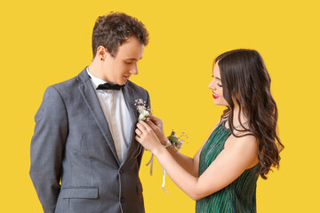 Canvas Print - Beautiful prom couple pinning boutonniere on yellow background