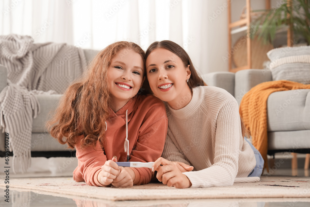 Happy young lesbian couple with pregnancy test at home