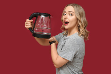 Wall Mural - Beautiful young woman with modern electric kettle on red background