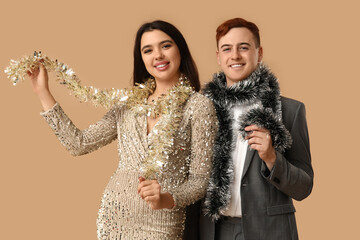 Sticker - Young couple with Christmas tinsel on brown background