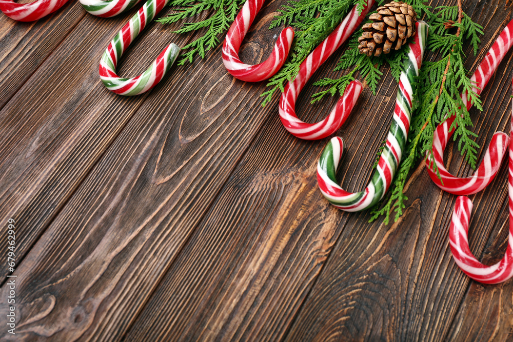 Christmas candy canes with coniferous branches and pine cone on wooden background