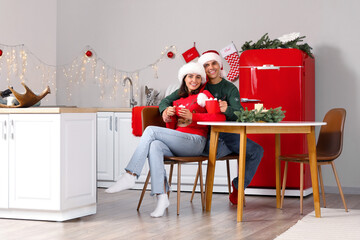 Sticker - Young couple drinking hot cocoa with marshmallows in kitchen on Christmas eve