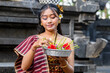 Young woman in traditional clothing making an offering at a temple