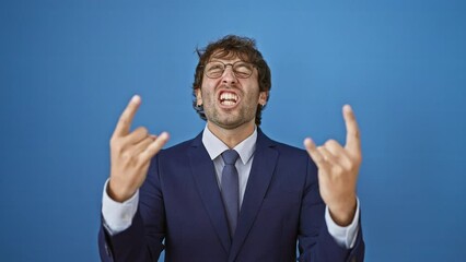 Canvas Print - Blue background craze, young man in business suit delightfully gesturing rock symbol with hands, embodying heavy music star concept!