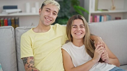 Sticker - Beautiful couple hugging each other sitting on sofa at home