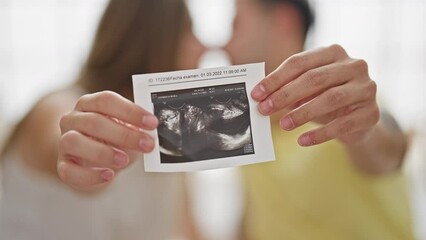 Sticker - Beautiful couple sitting on bed holding baby ultrasound kissing at bedroom