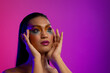 © Wavebreak Media - Biracial woman with dark hair, hands to head, pink lips, eyeshadow make up on purple background