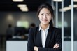 Confident businesswoman standing with arms crossed in modern office. asian