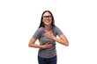 young positive brunette woman with glasses in a gray t-shirt with a mockup on a white background with copy space