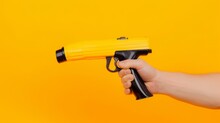Man Holds A Refueling Gun In His Hand For Refueling Cars Isolated On Yellow Background. Gas Station With Diesel And Gasoline Fuel Close-up