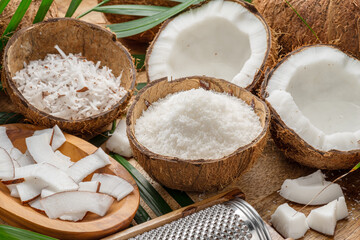 Wall Mural - Fresh opened coconuts along with coconut slices, flakes and coconut leaves on a wooden table.