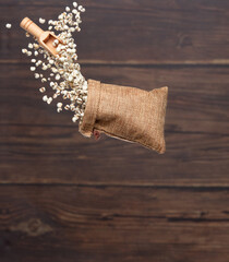 Wall Mural - Job's Tear flying in sack bag, white grain job tear float abstract cloud fly. Beautiful job's tear sack bag splash in air, food object design. Wooden background isolated high speed freeze motion