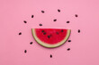 Piece of a watermelon sprinkled by seeds over pink background