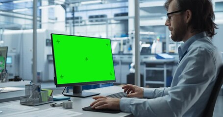Fototapete - Robotics Engineer Working on a Desktop Computer with Green Screen Chromakey Mock Up Display in a Startup Factory. High Tech Technological Research and Development Company with Autonomous Assembly Line