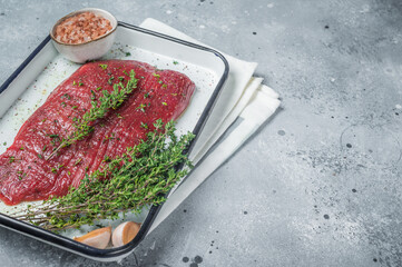 Poster - Marinatad flank beef steak with herbs and olive oil, raw meat. Gray background. Top view. Copy space