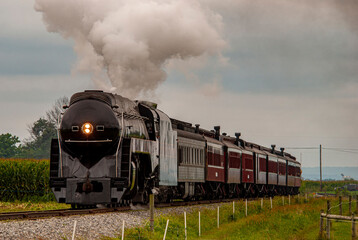 Canvas Print - A View of a Steam Passenger Train Approaching, Traveling Thru Rural America, Blowing Smoke on a Summer Day