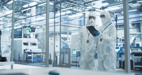 Leinwandbilder - Development Factory Cleanroom: Engineers Wearing Coveralls and Goggles while Talking and Using a Tablet Computer. Scientists Working in Advanced Electronics Manufacture with Precision Machinery
