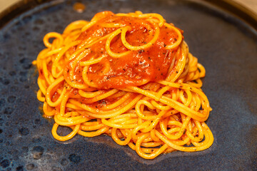 Wall Mural - Spaghetti pasta with tomato sauce close up on black plate